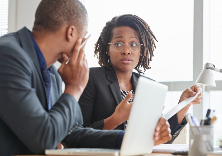 Surprised business lady in glasses talking to male coworker