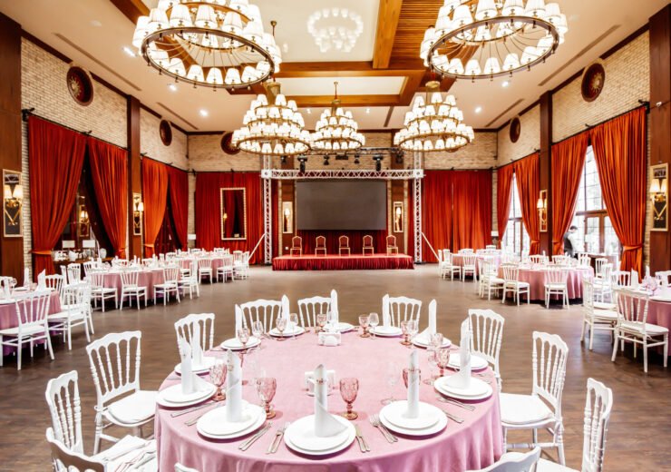 restaurant hall with small stage monitor red curtains brick walls white napoleon chairs