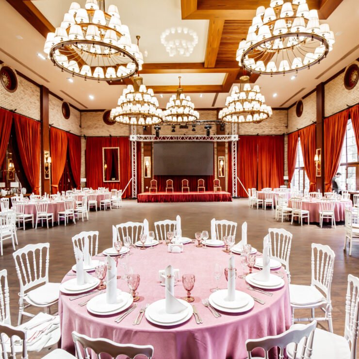 restaurant hall with small stage monitor red curtains brick walls white napoleon chairs restaurant hall with small stage monitor red curtains brick walls white napoleon chairs